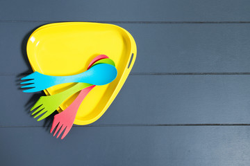 Multicolored plastic tableware on a wooden background. Hiking ki