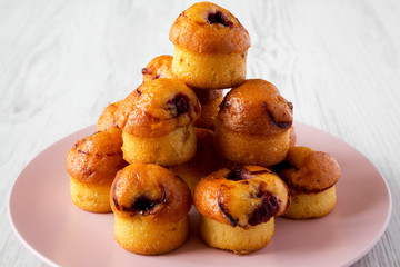 Homemade muffins with cherry on pink plate on a white wooden background, side view. Close-up.