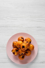 Homemade muffins with cherry on pink plate on a white wooden table, top view. Copy space.