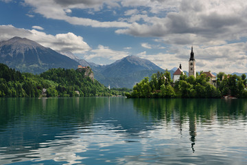 Stol and Begunjscica peaks of Karawanks mountains over Lake Bled with Assumption of Mary church on Island and Bled Castle Slovenia