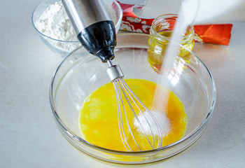 Eggs in a glass bowl with sugar.