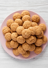 Almond cookies on pink plate over white wooden background, top view. Flat lay, overhead, from above. Close-up.