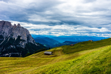 Fototapeta premium Alpe di Siusi, Seiser Alm with Sassolungo Langkofel Dolomite, a large green field with a mountain in the background