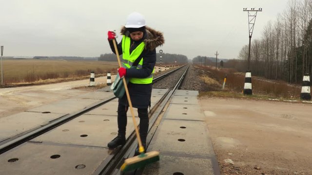 Female railway worker clean railway crossing and take break