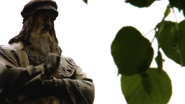 Leonardo Da Vinci Monument in Milan in a rainy day behind the leafs in Milan.