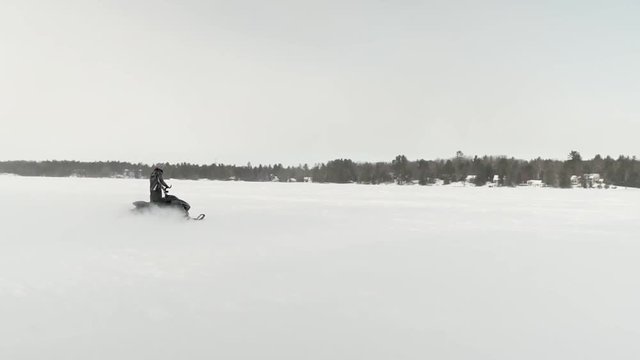 Slow motion footage of snowmobile taking of on frozen lake in Muskoka cottage country