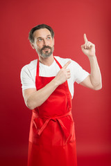 Inventing new dish. Cook with beard and mustache wear apron red background. Man mature cook posing...