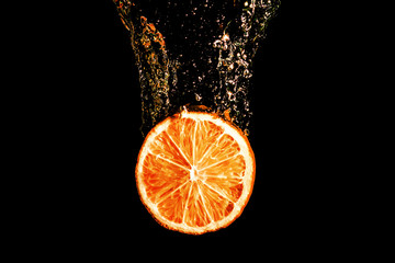 Fototapeta na wymiar Cut orange slice fruit splashing into water isolated on black background.