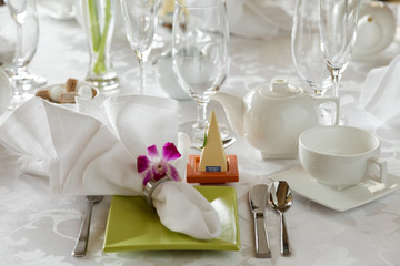 Elegant afternoon tea service with glasses, cups, and napkin setting on white linen table cloth
