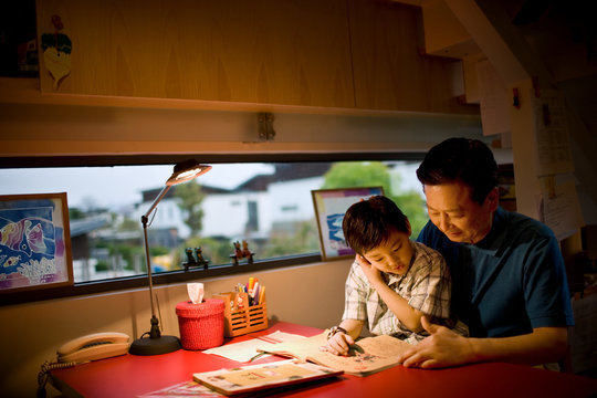 Mature man sitting reading with his son.