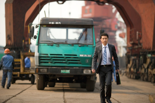 Young adult businessman walking on a wharf.