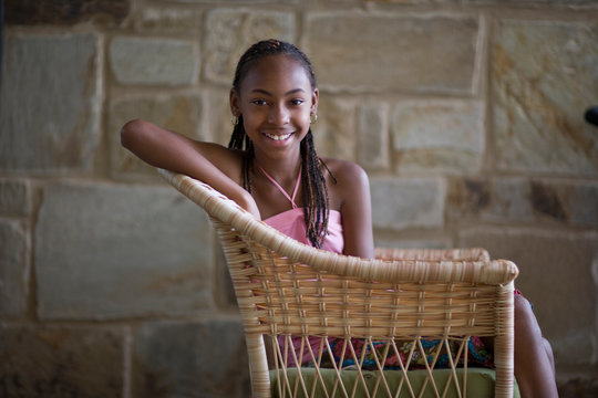 Portrait of a smiling teenage girl sitting in a wicker chair.