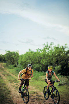 Adventurous young couple have a friendly race on their mountain bikes along a country lane.
