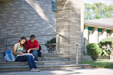 Teenage boy and girl studying on school steps