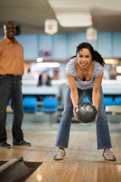 Smiling mid adult woman throwing a bowling ball.