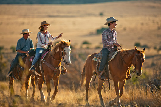 Happy family horseback riding through a rural field.