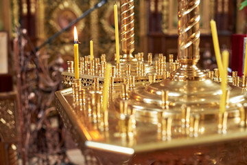 Candles in a golden chandelier in the Orthodox Church, close-up