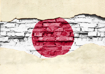 National flag of Japan on a brick background. Brick wall with partially destroyed plaster, background or texture.