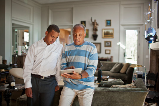 Mature man showing a digital tablet to his teenage son.