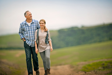 Smiling middle aged man walking with his teenage daughter.