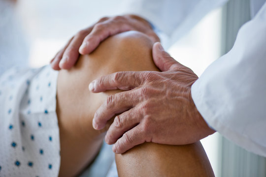 Doctor's hands examining a patient's knee.