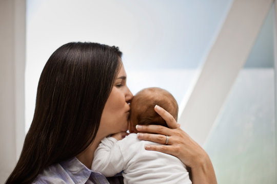 Mid adult woman kissing her baby.