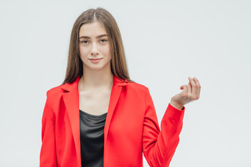 The young pretty girl is on a gray background. During this, he raised his hand, folded his fingers....