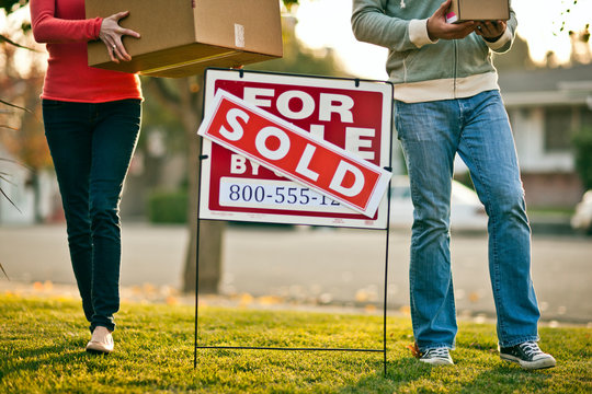 Couple arrive with boxes at their new home.
