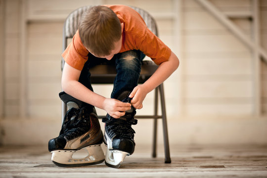 Young boy tying up the laces on his ice skates.