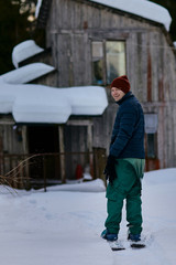 A man stands on skis in the forest on the background of an old wooden house.