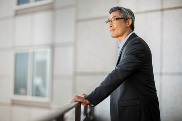 Pensive mature businessman taking a break on a balcony.