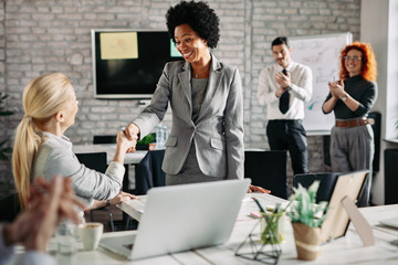 Happy African American businesswoman handshaking with her female colleague.