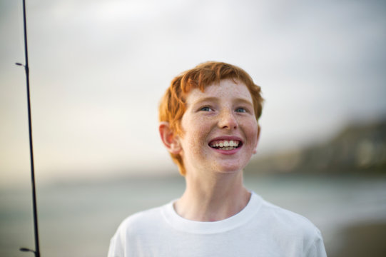 Smiling young boy standing on a beach.