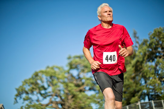 Active senior man running on a sports track.
