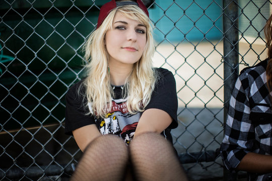 Blonde woman sitting against a fence