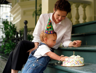 A mother watches her son blow a candle on his birthday.