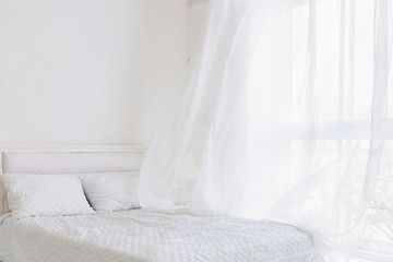 Abstract white bedroom interior. Curtains stirring in morning breeze