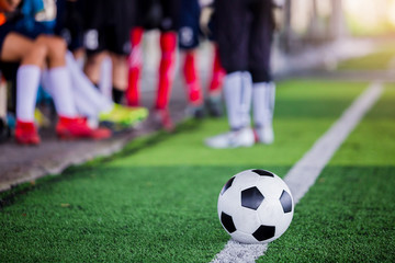 Obraz premium football on green artificial turf with blurry soccer players standing
