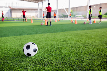 Obraz na płótnie Canvas football on green artificial turf with blurry soccer players