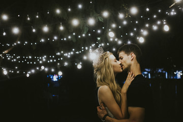 Young couple kissing under lights