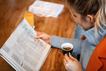 Close up of businesswoman reading newspaper while drinking coffee.