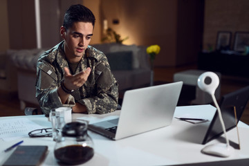 Young army soldier making video call over laptop.