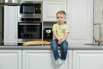 little funny boy eating a bun in the kitchen. cute baby eating baguette. Portrait of cute baby with bread in her hands. boy eat lunch in the kitchen