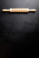 Rolling pin with a pattern in the form of stars on a black board. Baking Background .Preparation for cooking Food. Concept for Menu, Recipe, Ingredient. Copy space for Text.