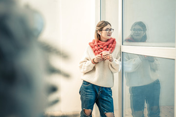 Good-looking stylish lady staying with cup of tea and wearing knitted outfit