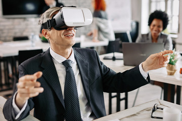 Playful businessman using virtual reality head set in the office.