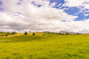 Alpe di Siusi, Seiser Alm with Sassolungo Langkofel Dolomite, a large green field with clouds in the sky