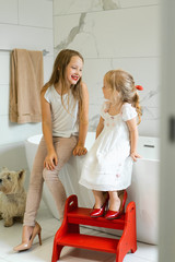 Mom and daughters do makeup in the bathroom, apply lipstick in front of the mirror. Daughters in...