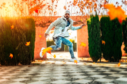 Man jumping in an autumn park with leaves falling