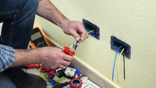 Electrician technician worker with cable cutter pliers cut the electric cable in a residential electrical system. Construction industry. Building. Footage. 